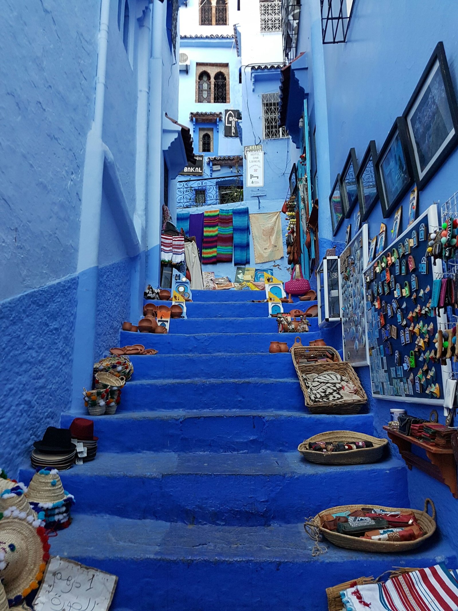 Woven baskets and crafts displayed on blue steps in Chefchaouen medina, Morocco