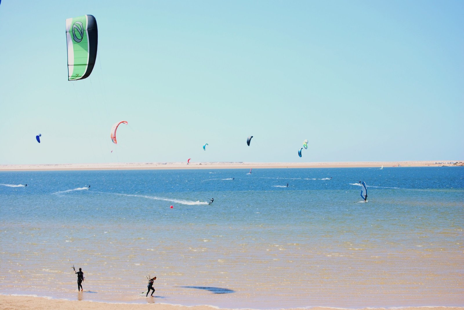 A kitesurfer glides across the flat turquoise water of the Dakhla lagoon