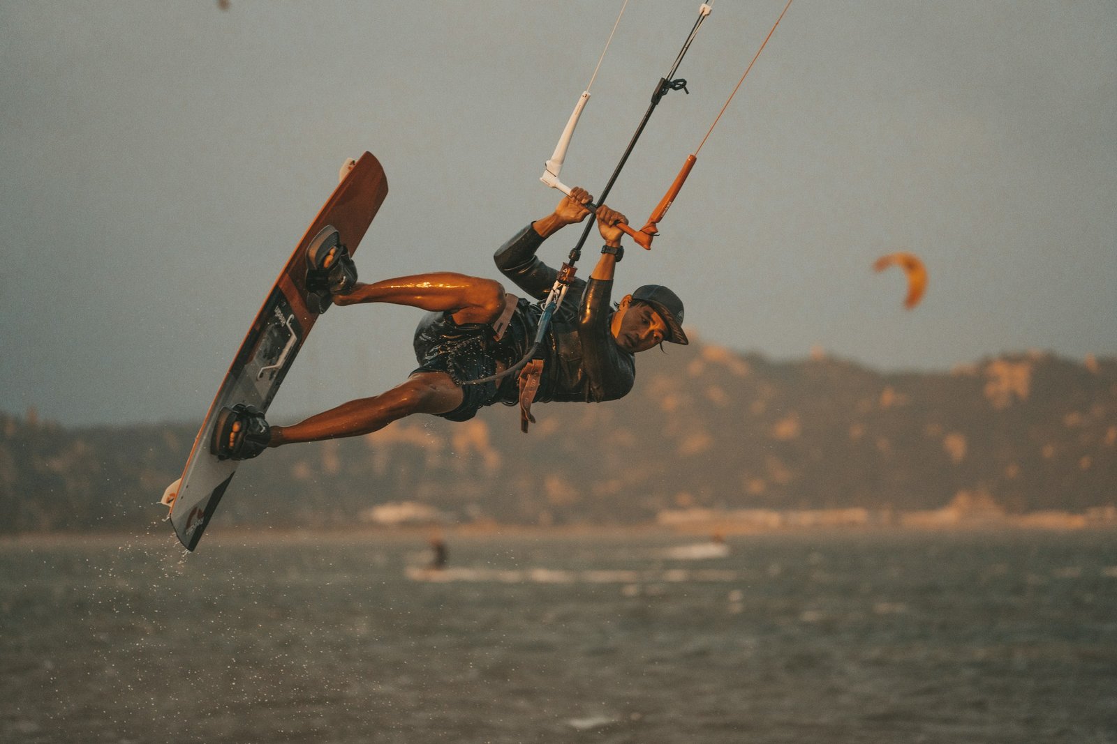 A kitesurfer holds the control bar while riding a kiteboard across the ocean