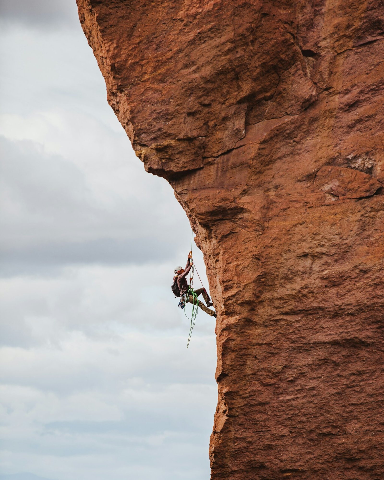 Climber ascending a sunlit rock face, similar to the bolted limestone routes found in Todra Gorge